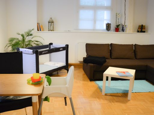 geräumiges Wohnzimmer mit Babybett und Kinderhochstuhl